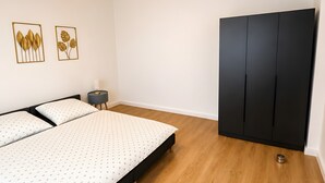 Een slaapkamer met een bed, een kledingkast, een nachtkastje en wanddecoratie.