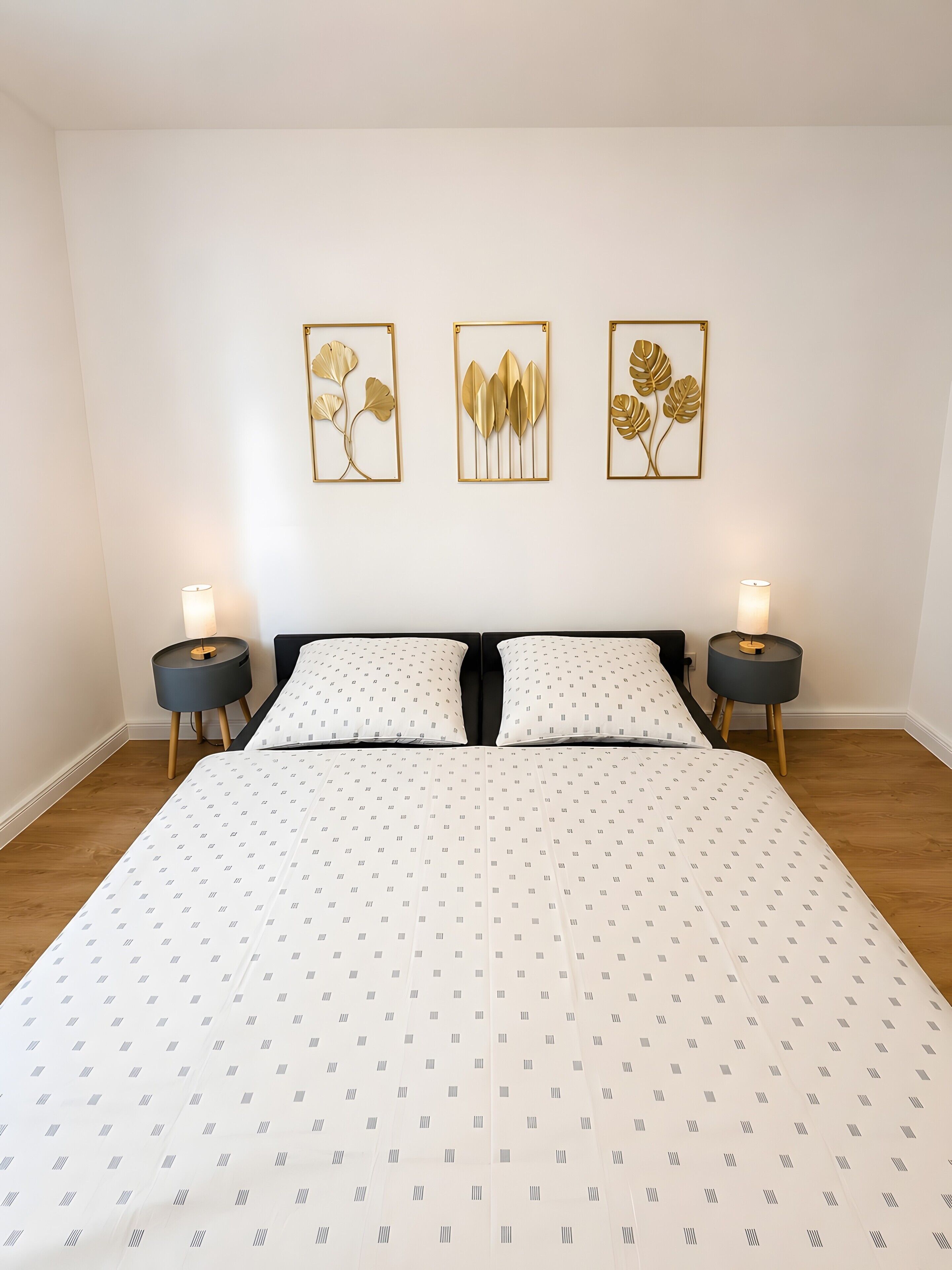 Ein Schlafzimmer mit einem großen Bett, zwei Nachttischen und drei an der Wand befestigten Kunstwerken.