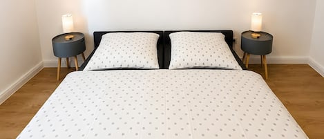 Un dormitorio con una cama grande, dos mesitas de noche y tres obras de arte colgadas en la pared.
