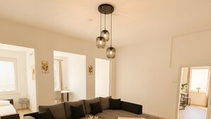 Een moderne woonkamer met een hoekbank, een salontafel en hanglampen.
