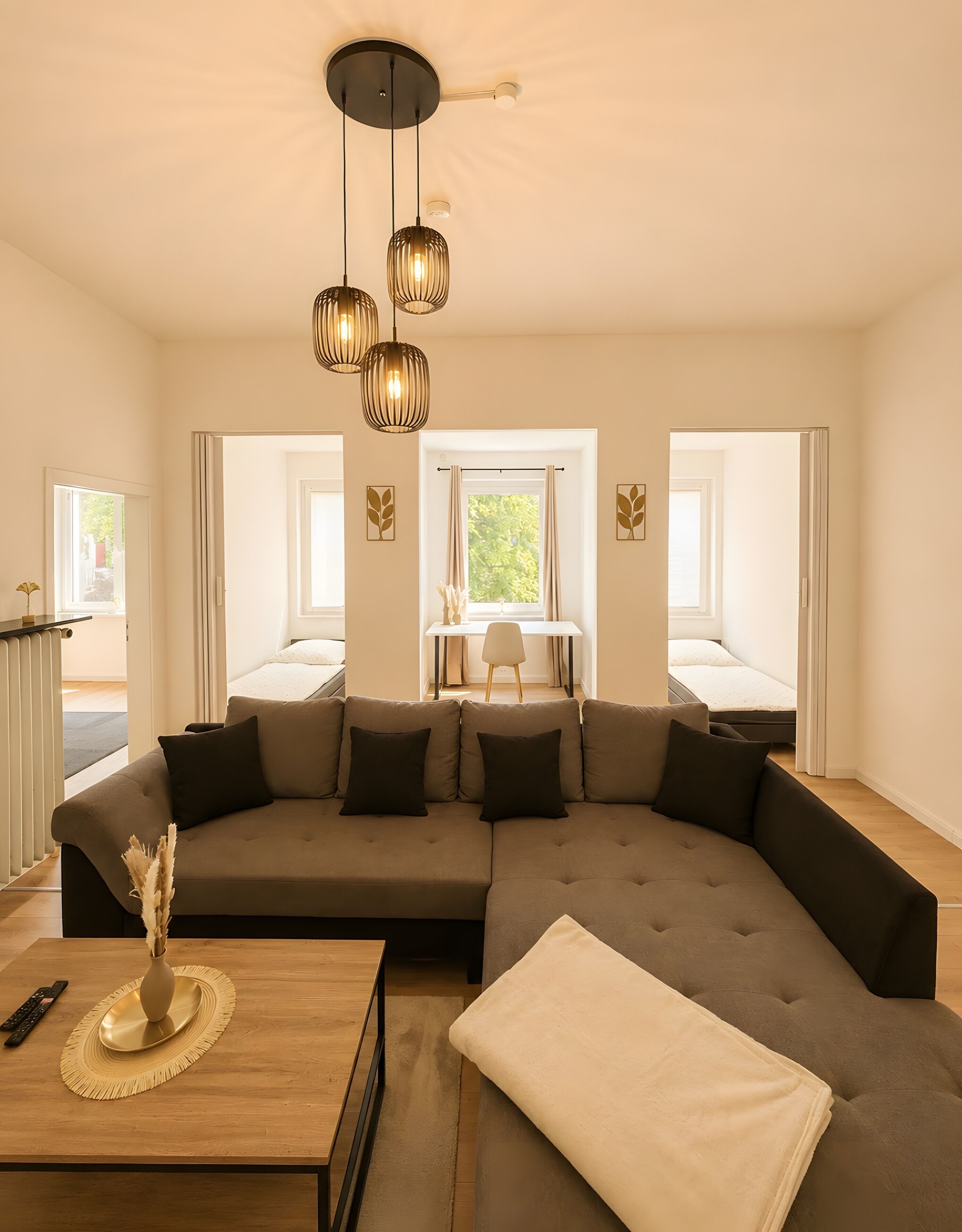 Ein modernes Wohnzimmer mit einem Ecksofa, einem Couchtisch aus Holz und einer Pendelleuchte.
