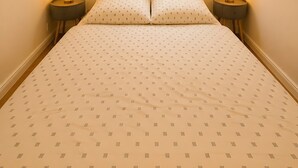 Ein Schlafzimmer mit einem Bett, zwei Nachttischen, einem Fenster mit Jalousien und Wandbildern.