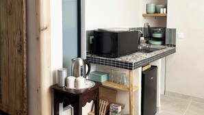 Cocina compacta con microondas, hervidor y cafetera sobre una mesita.