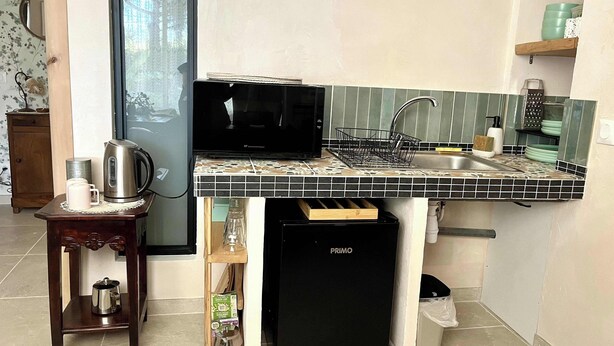 Cocina compacta con microondas, pileta y heladera pequeña.