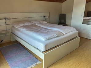 Ein modernes Schlafzimmer mit Bett, Nachttisch und Kleiderschrank.
