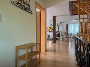 Eine hölzerne Bank, ein an der Wand befestigter Kleiderhaken, ein Blumentopf, ein Kamin und ein Essbereich mit Stühlen und einem Tisch.