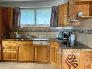 A kitchen with wooden cabinets, a dishwasher, and a window with curtains. - Domizil Seeidyll Appartement/Fewo Appartement/Fewo by Interhome (Spiez)