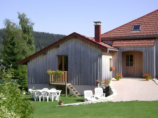 A wooden house with a red roof, a front porch, and a small window.