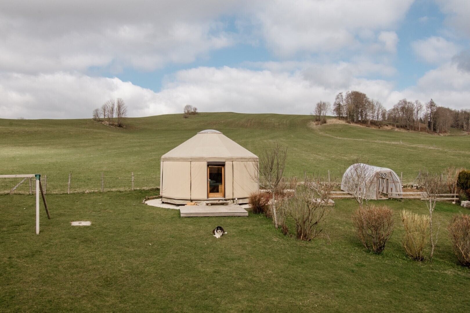 A yurt with an open door, situated on a grassy hill with a clear sky.
