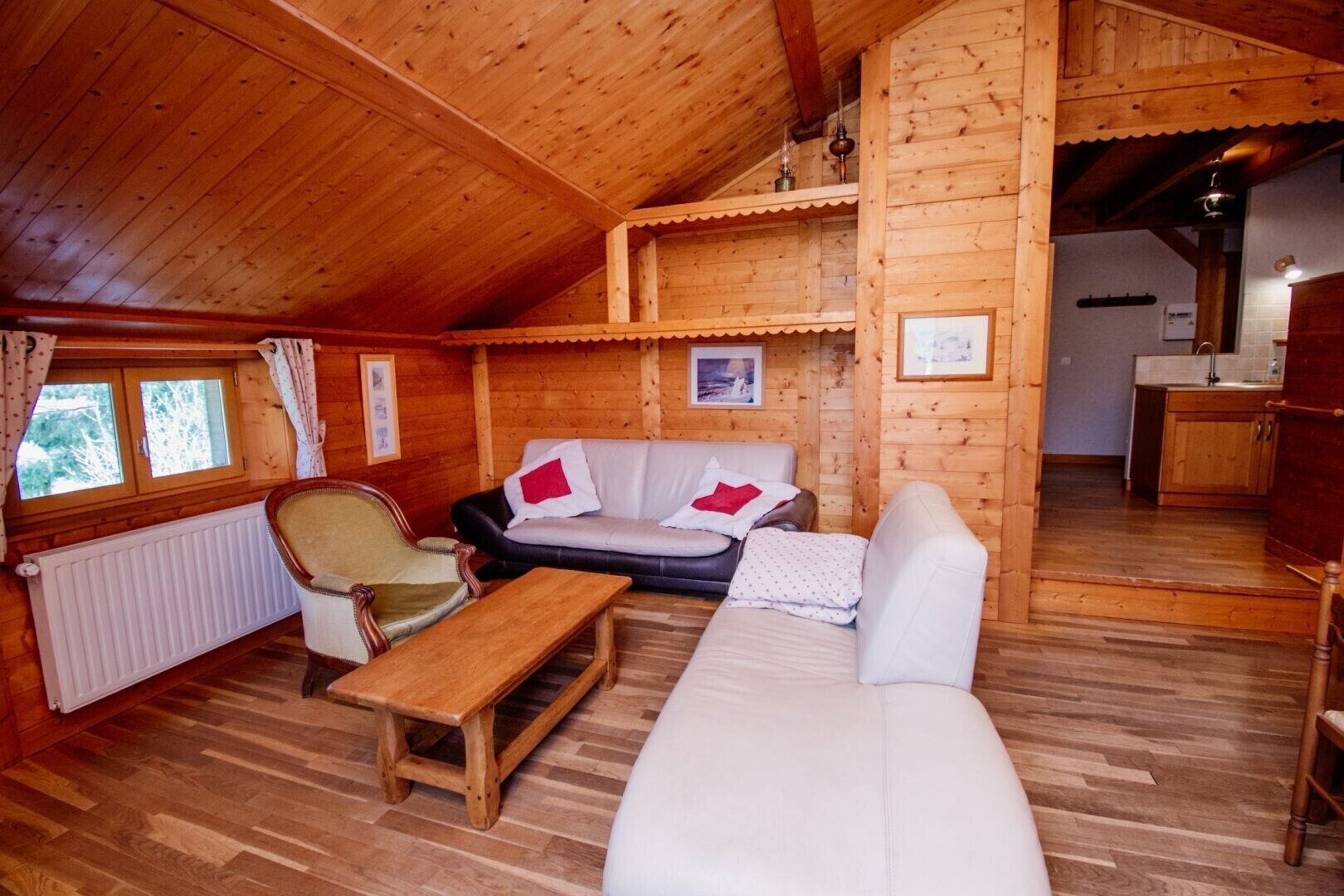 L’intérieur d’un chalet en bois chaleureux et accueillant, avec un canapé, un fauteuil et une petite table.