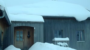 Un edificio de madera con techo nevado y una sola puerta.