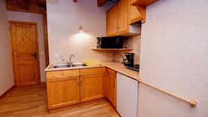 Una cocina con armarios de madera, un lavamanos, lavavajillas y cafetera.