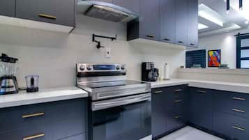 Cocina moderna con gabinetes oscuros, electrodomésticos de acero inoxidable y una cafetera.