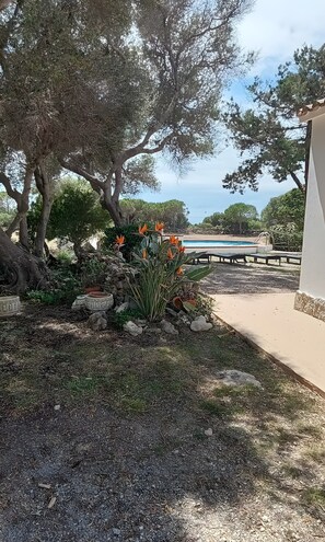A garden with a pool, trees, and a paved walkway. - Holiday Home 'Casa En El Campo Con Vistas Al Mar' with Private Pool, Private Terrace and Wi-Fi (Maó)