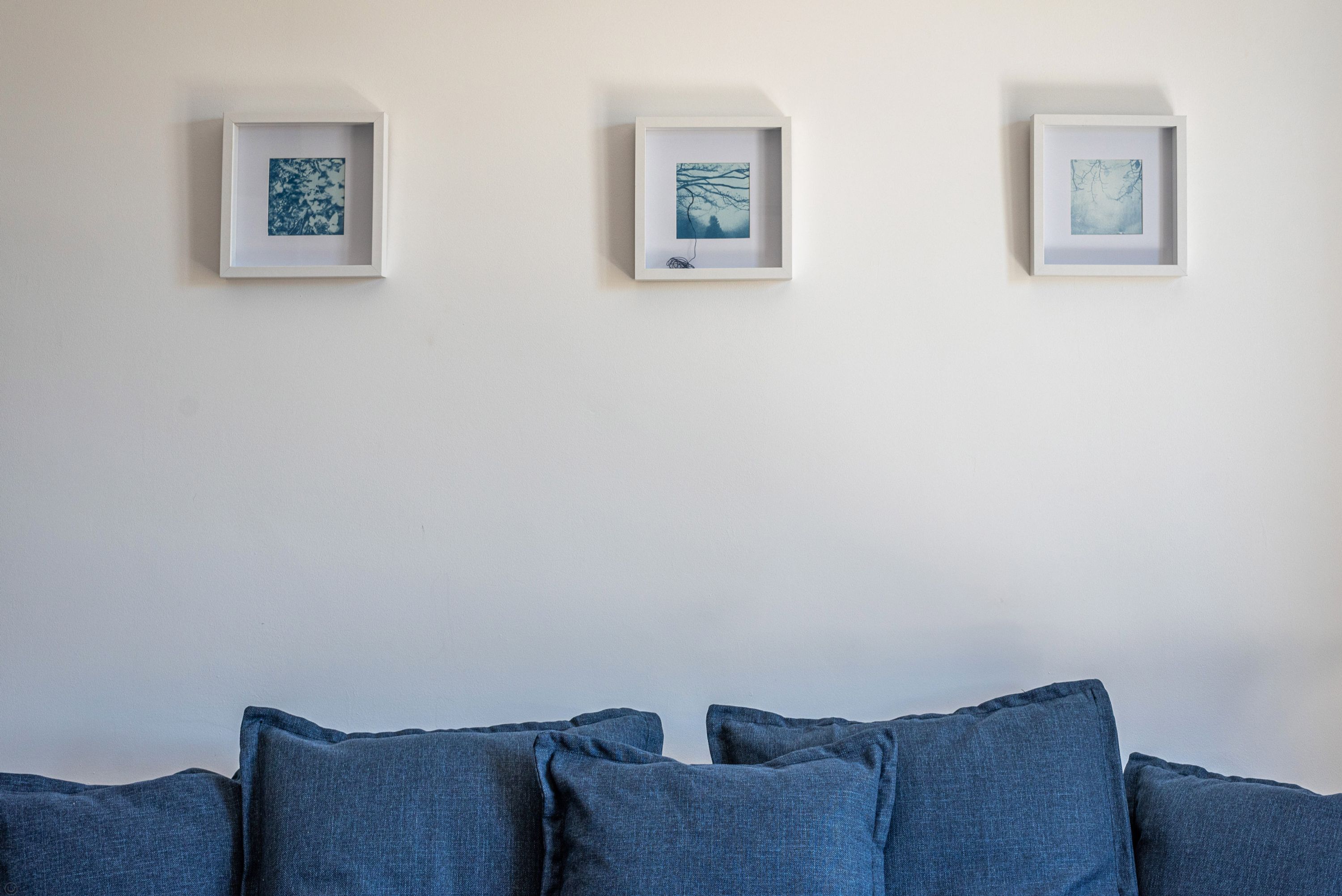 A room with a white wall and three framed artworks.
