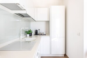 A modern kitchen with white cabinetry, a built-in stove, and a coffee maker on the countertop. - Igiea Florio Sea View by Wonderful Italy (Palermo)