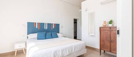 A bedroom with a bed, a nightstand, a wooden cabinet, and a mirror.