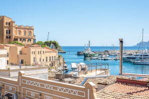 A coastal marina with boats docked, a large building with arched windows, and a clear blue sky. - Igiea Florio Sea View by Wonderful Italy (Palermo)