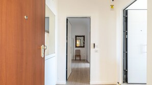 Ein Flur mit einer Holztür links, einer weißen Tür rechts und einem Spiegel an der Wand.