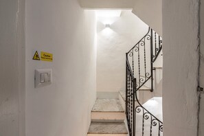 Eine Treppe mit Warnschild, Lichtschalter und Metallgeländer.