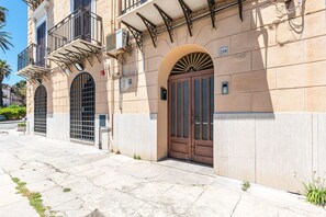 A building with a large arched entrance, a balcony with metal railings, and a sign indicating the number 228.
