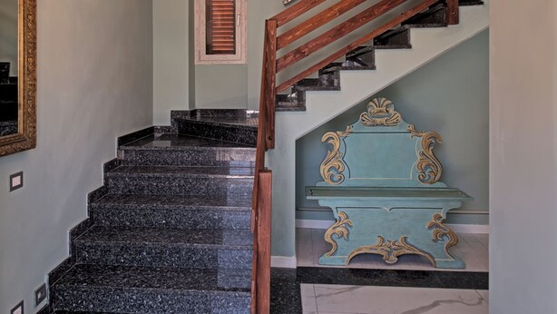 A staircase with a wooden handrail and a blue accent wall. - B&b Villa Ravenna (Ravenna)
