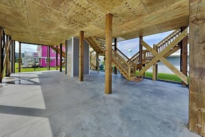 Ein offenes Raumkonzept mit freiliegenden Holzbalken, einem Betonboden und einer Treppe, die zu einer oberen Ebene führt.