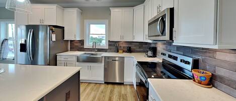 A modern kitchen with white cabinets, stainless steel appliances, and a large island.