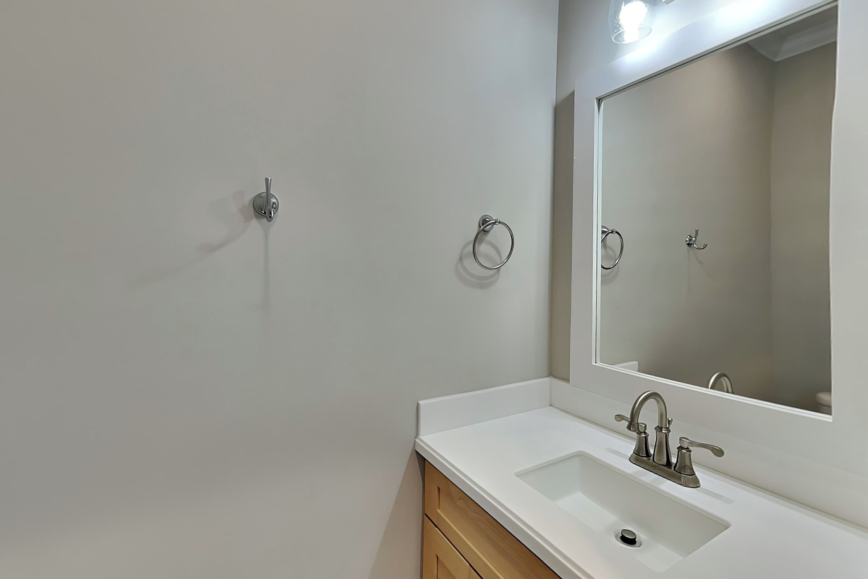 A bathroom with a white sink, a mirror, and a towel ring on the wall.