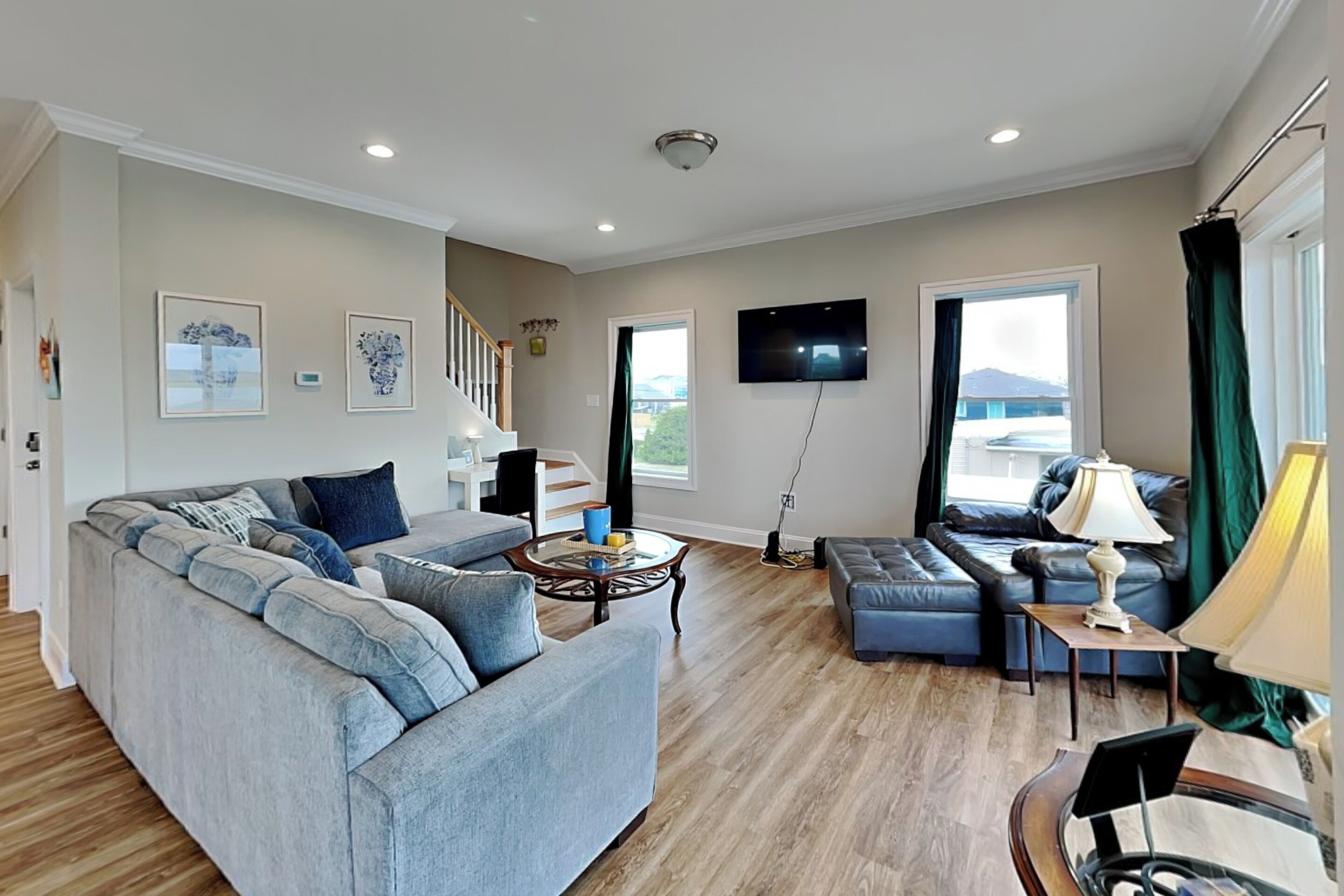 A living room with a large grey sofa, a coffee table, a TV, and a staircase leading to another level.