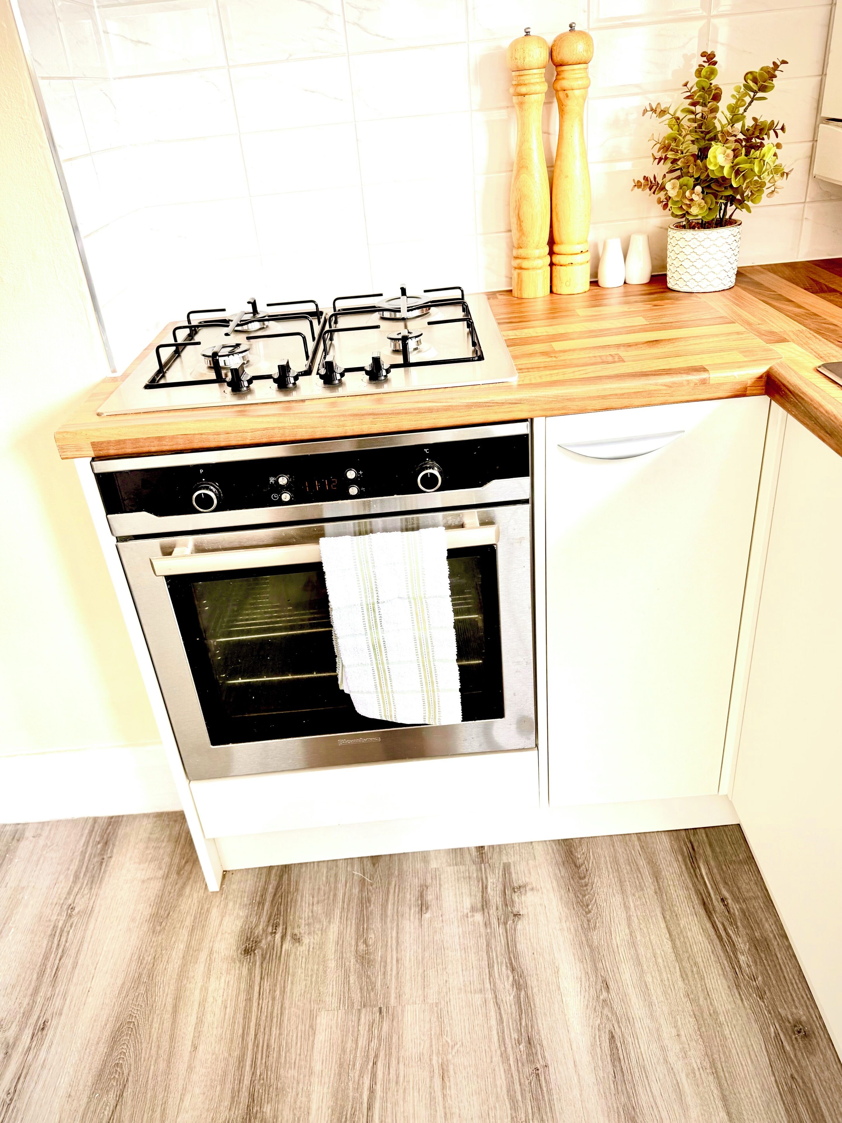 A kitchen with a gas stove, oven, and wooden countertop.