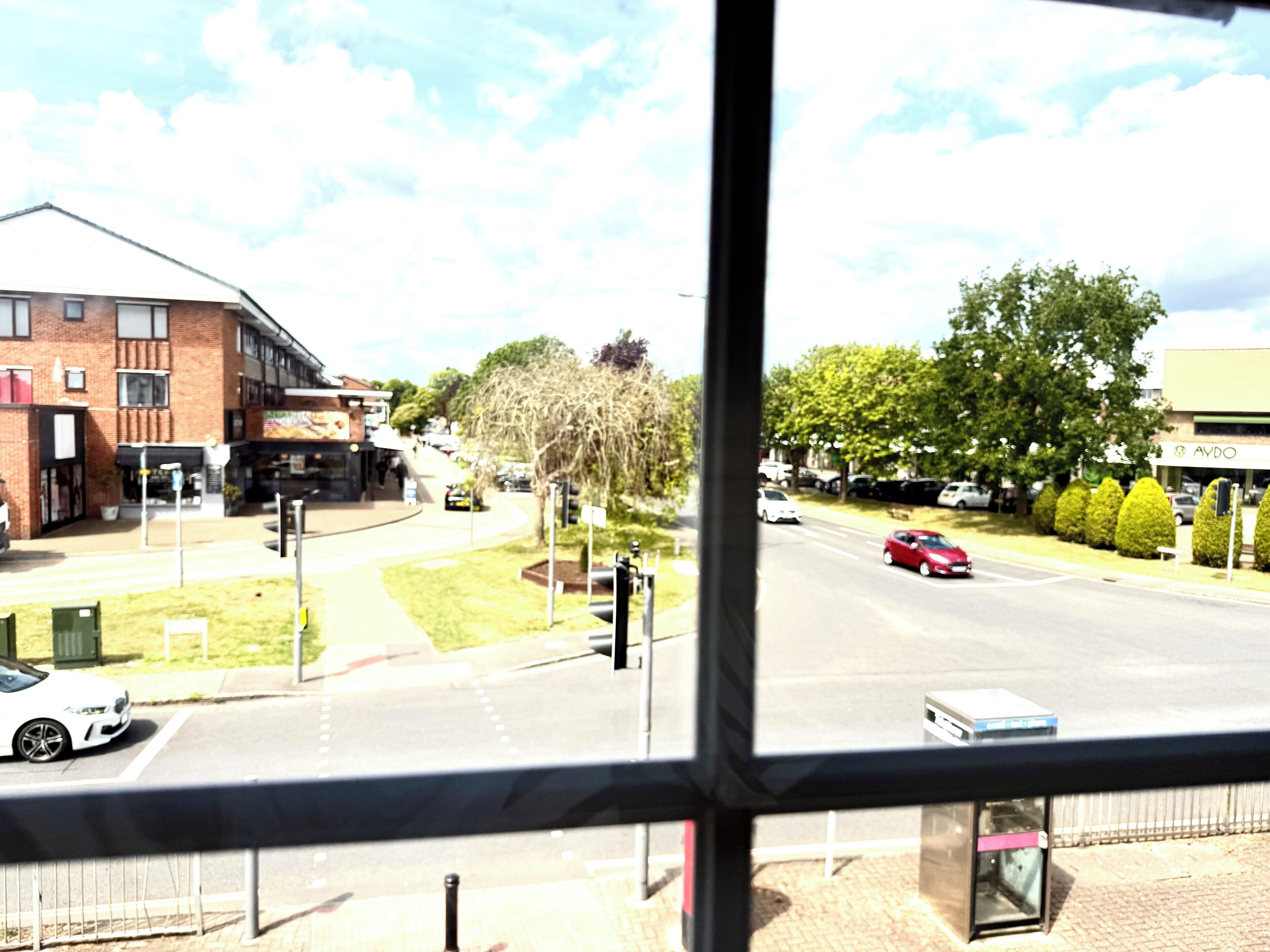 Vista de la calle con edificios, una carretera y coches estacionados.