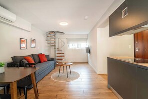 A modern living space with a spiral staircase, a dining area, and a kitchen. - Stylish Duplex Apartment Near Victoria Metro (Athens)