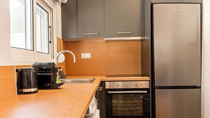 Una cocina compacta con un refrigerador de acero inoxidable, un horno empotrado y una cafetera sobre la encimera.