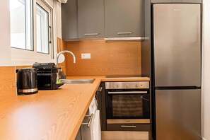Eine kompakte Küche mit Edelstahl-Kühlschrank, integriertem Backofen und einer Kaffeemaschine auf der Arbeitsfläche.