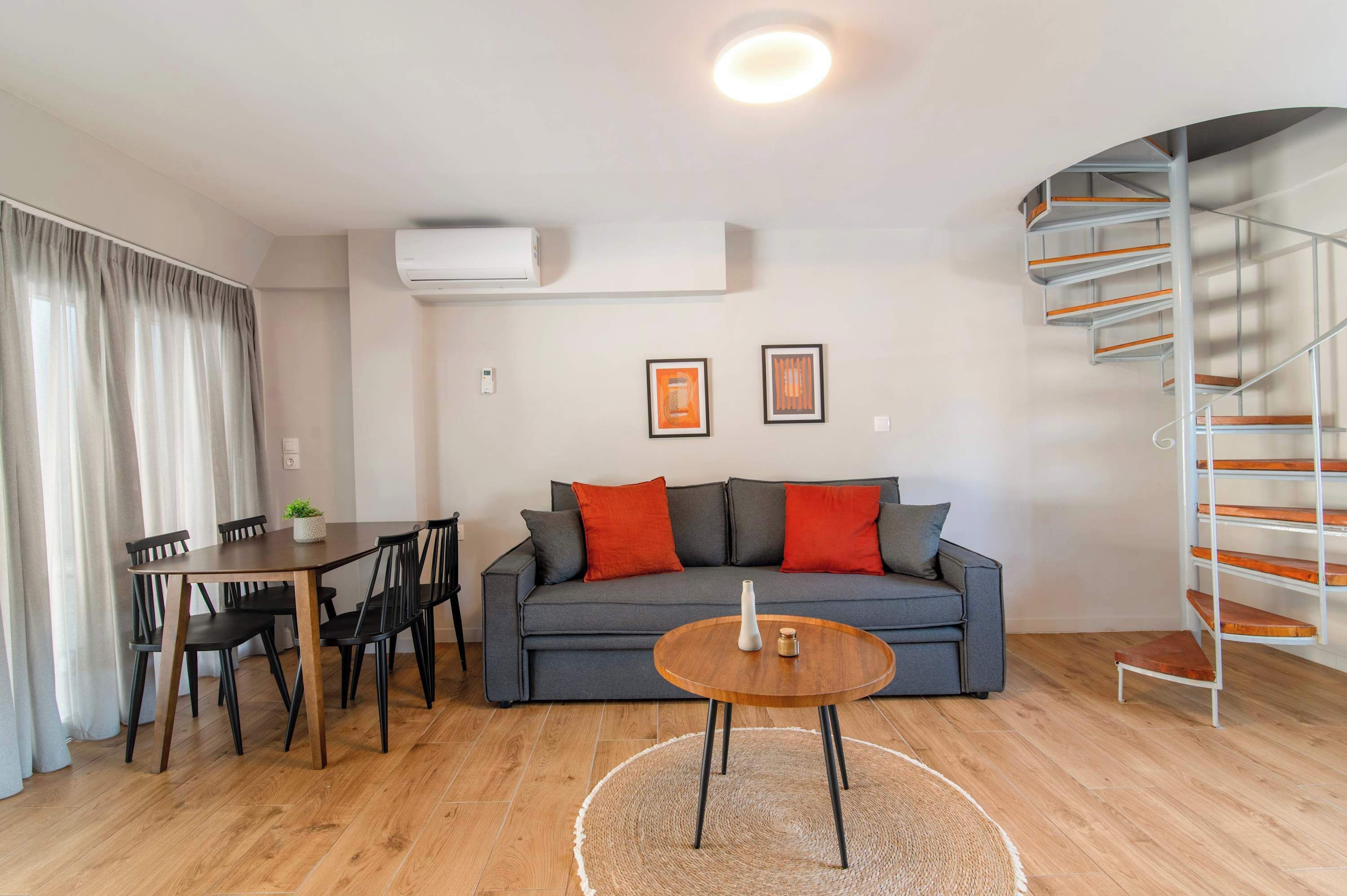 Un salon moderne comprenant un canapé, une table à manger, des chaises, une table basse, un escalier et un appareil de climatisation.