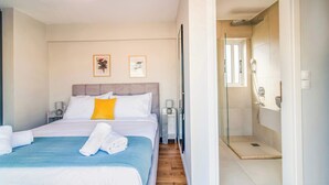 Habitación de hotel con cama, mesita de noche, ducha y dos cuadros en la pared.