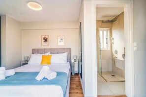 Ein Hotelzimmer mit einem Bett, einem Nachttisch, einer Dusche und zwei gerahmten Bildern an der Wand.
