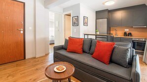 A modern living room with a gray sofa, red cushions, and a small wooden table with a plate of food. - Modern Athens Apartment Near Attractions (Athens)