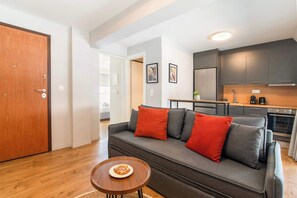 Ein modernes Wohnzimmer mit einem grauen Sofa, roten Kissen und einem kleinen Holztisch mit einer Schüssel Essen.