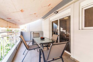 A balcony with a table and chairs, a glass door, and a view of the outside. - Modern Athens Apartment Near Attractions (Athens)