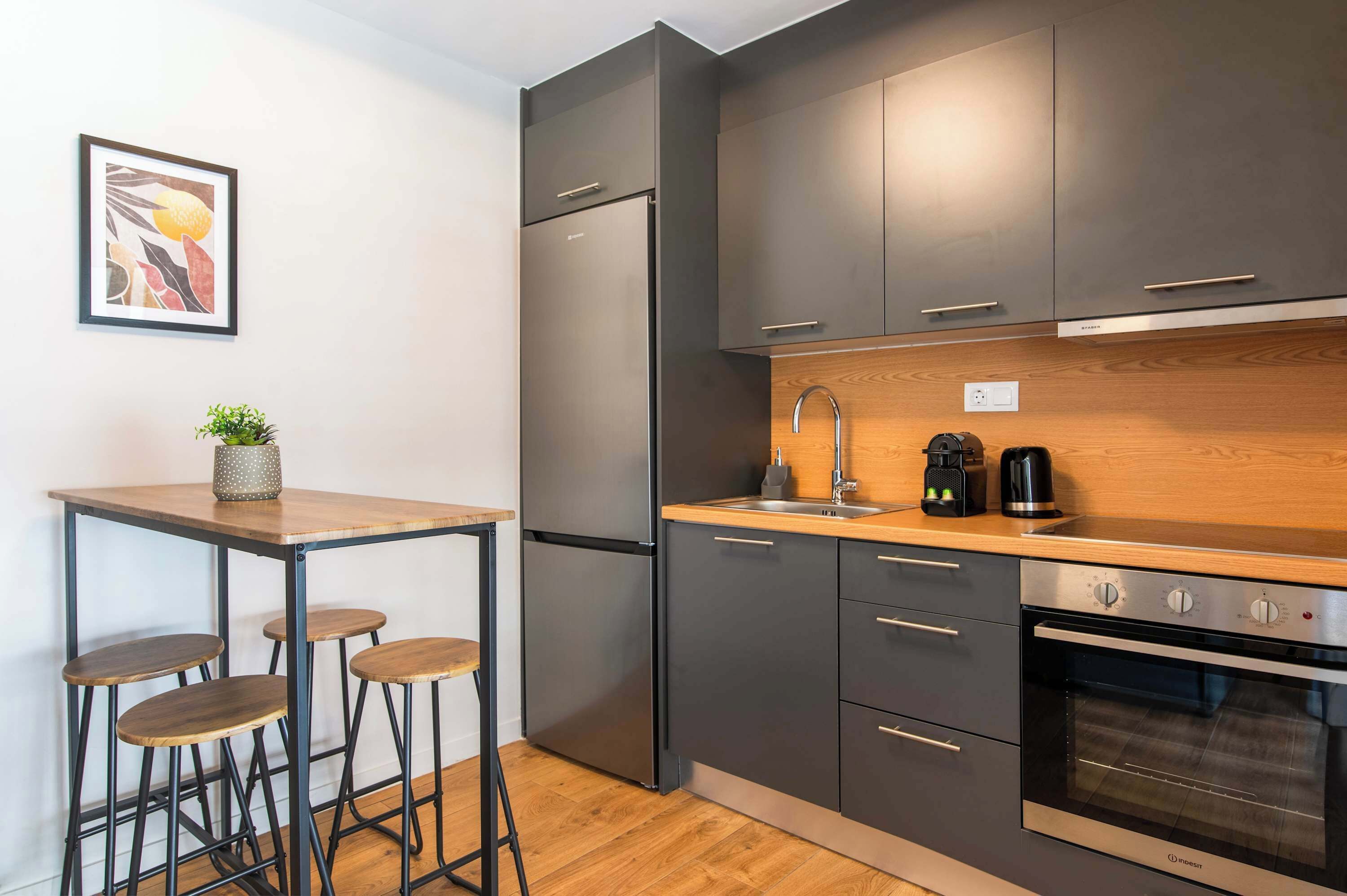 Una cucina moderna con frigorifero in acciaio inossidabile, forno integrato e piano di lavoro in legno.