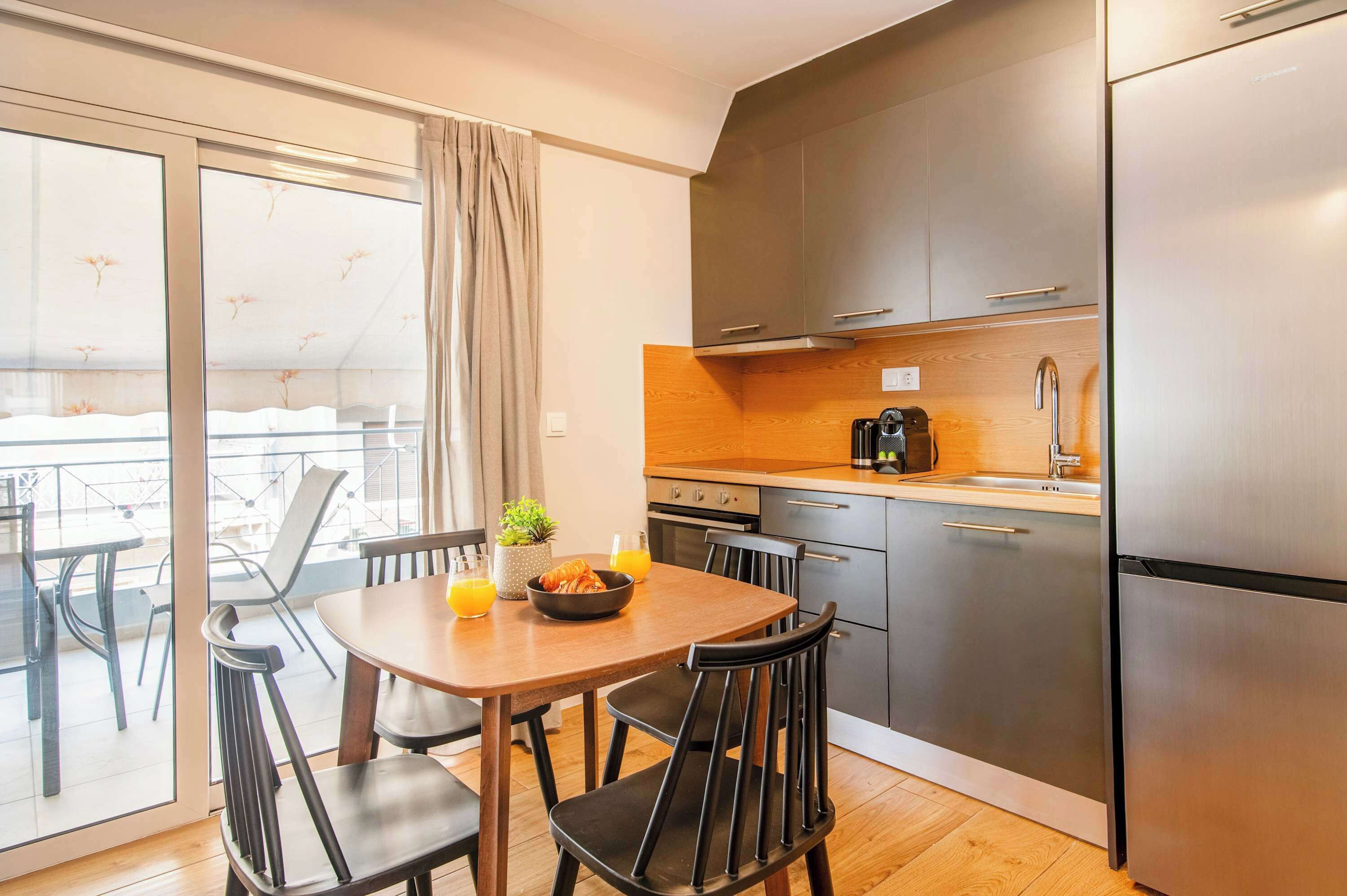 Une cuisine moderne avec un coin repas, un réfrigérateur et une vue sur l’extérieur.