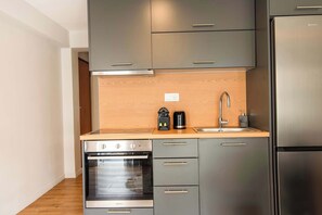 Een moderne keuken met roestvrijstalen apparatuur, een houten aanrechtblad en grijze kastjes.