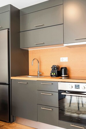 A modern kitchen with a stainless steel refrigerator, a built-in oven, and a coffee maker on the countertop. - Modern Athens Apartment Near Metro Station (Athens)