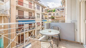 A balcony with a round table and two wicker chairs, surrounded by a metal railing. - Modern Athens Apartment Near Metro Station (Athens)
