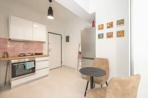 Eine moderne Küche mit weißen Schränken, einem Edelstahl-Kühlschrank und einem Essbereich mit rundem Tisch und Stühlen.