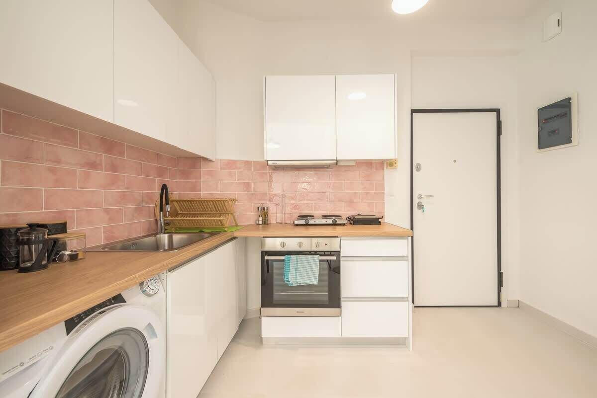 A compact kitchen with a washing machine, a stove, and a sink.