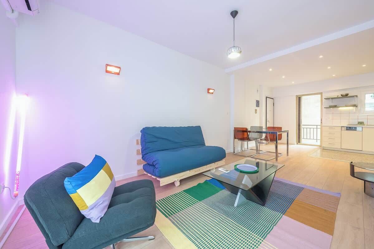 A modern living room with a sofa, a glass coffee table, and a dining area with chairs.