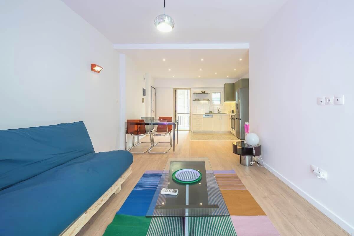 A modern living room with a sofa, a glass coffee table, and a dining area with chairs.